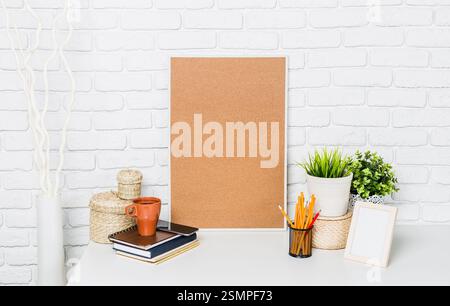 Kreativer Arbeitsbereich mit leerem Pinnwand, Topfpflanzen und gemütlichem Büromaterial in einem gut beleuchteten Raum Stockfoto