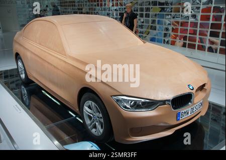 Designkonzept für BMW-Fahrzeuge. Ein schwarzer Hintergrund zeigt das BMW-Logo, die 3er-Schriftzug und ein F30-Tonmodell, das die konzeptionelle Designphase repräsentiert Stockfoto