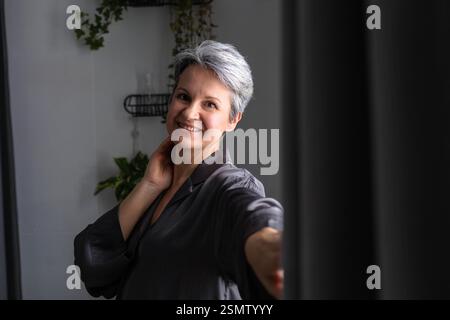 Reife schöne und gepflegte Frau während der Wechseljahre mit grauem Haar posiert. Stockfoto