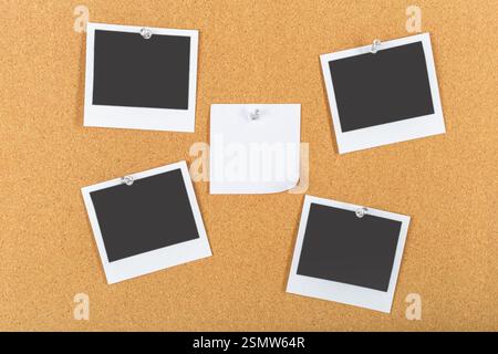Sammlung von leeren Polaroiden auf Korkbrett mit einer einzigen Haftnotiz in der Mitte Stockfoto