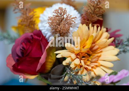 Ein sorgfältig gestalteter Strauß mit Rosen, Gänseblümchen und dekorativen Elementen in warmen Farben. Das lebhafte Display bringt herbstlichen Charme und natürliche bea Stockfoto