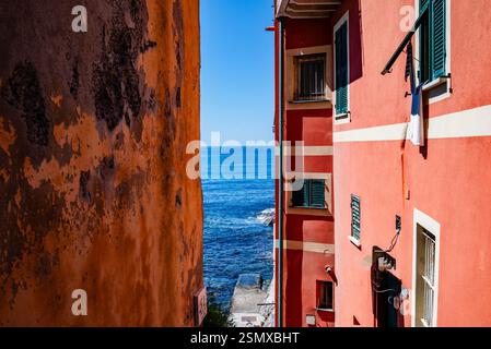 Werfen Sie einen Blick auf das blaue Meer zwischen den hohen bunten Häusern im Fischerdorf Boccadasse, Ligurien, Italien Stockfoto