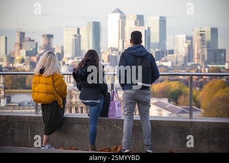 Freunde hängen in Greenwich Hill mit Canary Wharf City im Hintergrund in London, Großbritannien Stockfoto