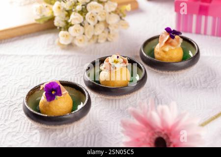 Köstliche herzhafte Käsebällchen mit parmaschinken und essbaren Blumen schmücken einen festlichen Tisch Stockfoto