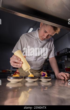 Koch garniert kleine Gerichte mit Sauce in der Restaurantküche Stockfoto
