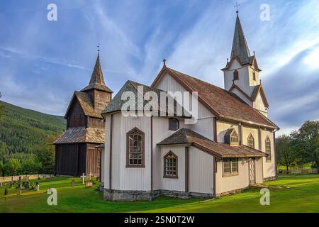 Weiße Holzkirche mit braunem Dach und Glockenturm neben einem alten Holzgebäude mit Friedhof. Torpo, Ål, Buskerud, Norwegen, Europa Stockfoto