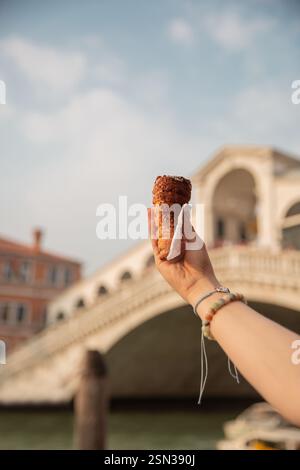 Eine Frau hält Donut-Kegel vor der Rialto-Brücke in Venedig, Italien Stockfoto