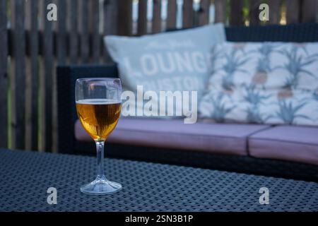 Ein Glas Weißwein auf einem Tisch auf einer Terrasse mit Kissen Stockfoto
