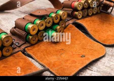 Detaillierte Aufnahme eines Munitionsgürtels aus Leder, gefüllt mit Schrotflintenschalen auf einer rustikalen Holzoberfläche Stockfoto