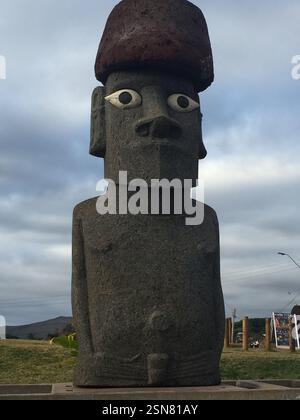 Eine bemerkenswerte Moai-Statue, die aus vulkanischem Felsen geschnitzt wurde, ragt über die Landschaft auf Rapa Nui. Die Figur zeichnet sich durch besondere Gesichtsmerkmale aus Stockfoto