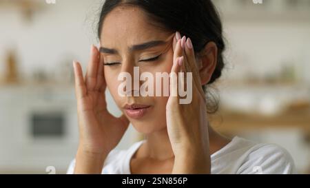 Krank krank krank müde erschöpft ermüdet leiden schlechtes Gefühl Arabische Frau indische Frau Frau Frau zu Hause Migräne Schmerzen Kopfschmerzen schmerzhafte Kopfschmerzen Symptom Stockfoto