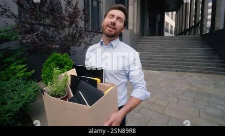Glückliches Singen lächelnd Gehen in Stadt Mann Geschäftsmann männlicher Kerl Geschäft entlassen Büro beenden Firma arbeiten halten Tragen Entlassungsbox neu Stockfoto