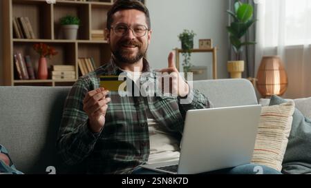 Kaukasischer Mann männlicher Kerl zu Hause glücklich lächelnd mit Kreditkarte kaufen Online-Internet-Banking Pay-Buy-Shopping Kauf Kauf Kauf Kauf Kauf Kauf Zahlung Erfolg Stockfoto
