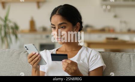 Online-Internet-Zahlung ernsthafte indische Frau arabische weibliche ethnische Mädchen zu Hause Hindu-Dame, die auf Handy mit Smartphone-Halten Gadget Stockfoto
