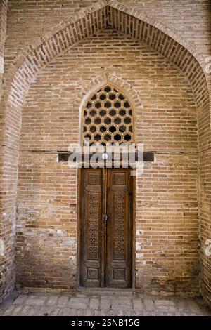 Typischer Eingang mit Holztür in der Spitzbogennische in Buchara in Usbekistan Stockfoto