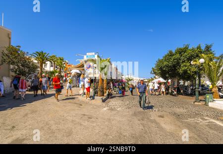 Touristen genießen einen Nachmittag mit Geschäften und Restaurants in Cafés entlang der Haupttouristenstraße in Fira auf Santorin, Griechenland. Stockfoto