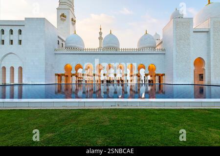 Beleuchtetes Inneres durch Schlüsselbogenbögen unter arabischen Kuppeln und Minaretten in der Scheich-Zayed-Moschee in Abu Dhabi, Vereinigte Arabische Emirate. Stockfoto