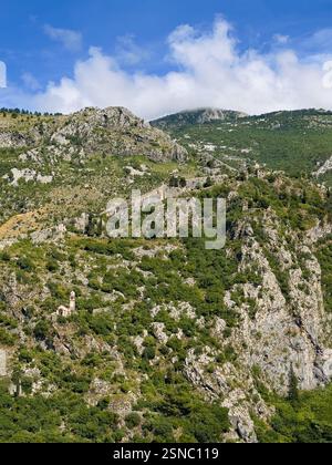 Kotor, Montenegro - 2. Juli 2024: Kirche unserer Lieben Frau von Remedy auf dem grünen bewaldeten Berg und darüber die Festungswälle unter blauer Wolkenlandschaft Stockfoto