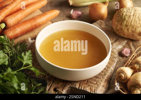 Hühnersuppe oder Knochenbrühe in einer weißen Schüssel mit frischem Gemüse Stockfoto