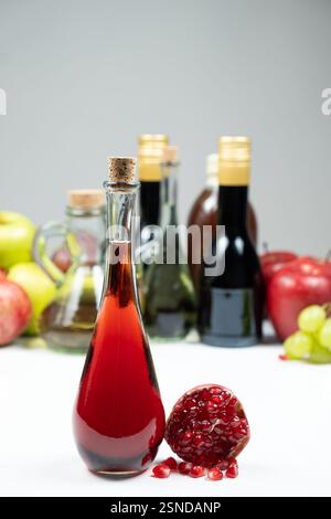 Granatapfelessig vor dem Hintergrund von Früchten und anderen Essigsorten Stockfoto
