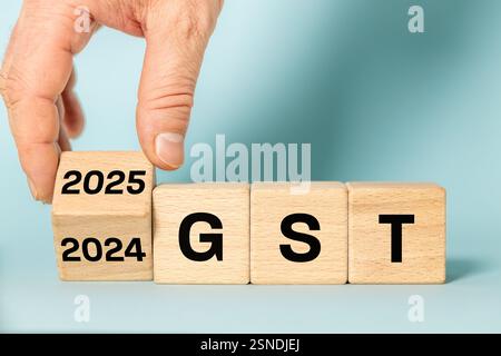 gst 2025. Neues Steuerjahr. Symbol für finanzielle Abrechnungen. GST auf Holzblöcken geschrieben. Bewegen Sie das Datum von 2024 auf 2025. Wunderschöner blauer Backgrou Stockfoto