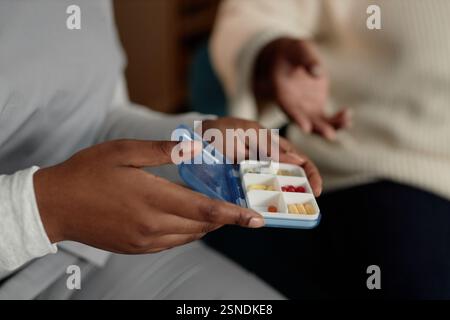 Nahaufnahme an den Händen einer Krankenschwester, die einen kleinen Pillen-Kasten-Organisator mit Medikamenten hält, die der älteren Frau das Rezept erklären, während sie den Patienten zu Hause besucht, Kopierraum Stockfoto