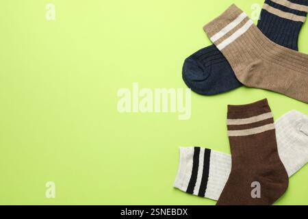 Verschiedene bequeme Socken auf hellgrünem Hintergrund, flach geschnitten. Leerzeichen für Text Stockfoto