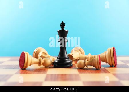Schwarzer Schachkönig unter anderen gefallenen weißen Spielfiguren auf dem Schachbrett. Wettbewerbskonzept Stockfoto