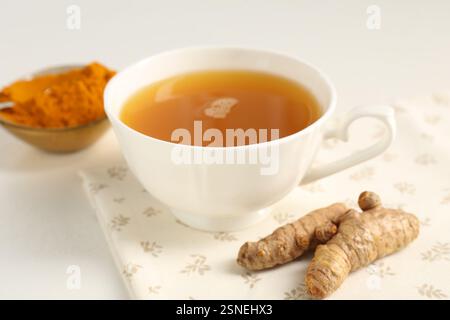 Aromatischer Kurkuma-Tee, Pulver und Rhizome auf weißem Tisch, Nahaufnahme Stockfoto