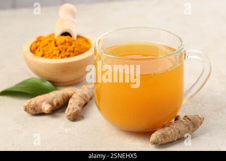 Aromatischer Kurkuma-Tee, Rhizome und Pulver auf weißem texturiertem Tisch, Nahaufnahme Stockfoto