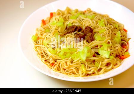 Asiatische gebratene Nudeln mit Kohl, Rindfleisch und Gemüse, serviert auf einem weißen Teller. Traditionelle hausgemachte Mahlzeit Stockfoto