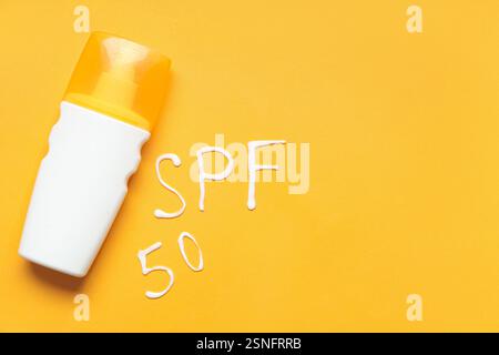 Flasche Sonnencreme und Text SPF 50, geschrieben mit Creme auf farbigem Hintergrund Stockfoto