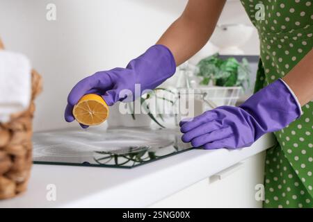 Hausfrau putzt elektrischen Herd mit Zitrone und Backpulver in der Küche, Nahaufnahme Stockfoto