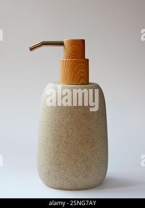 Ein schön gestalteter Seifenspender mit strukturiertem Steinkörper mit einer Holzpumpe und einem Edelstahlauslauf, der natürliche Materialien mit Mo vermischt Stockfoto