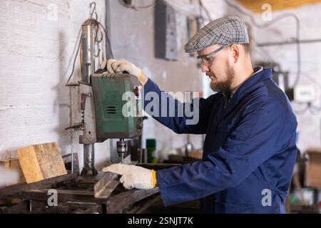 Junger Mann bohrt Löcher in Metallteile Stockfoto