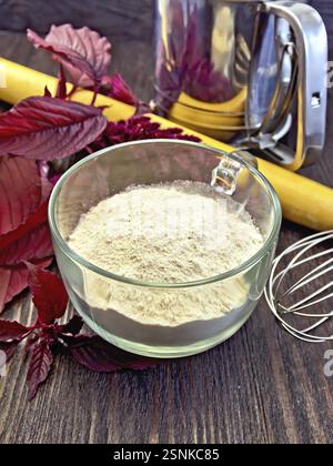 Amaranth Mehl in einem Glasbecher, Mixer, Nudel und Sieb, lila Amaranth Blüte auf dem Hintergrund von Holzbrettern Stockfoto