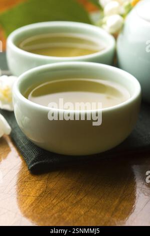 Grüner Tee mit Jasmin in der Tasse und Teekanne auf Holztisch, lodz, polen Stockfoto