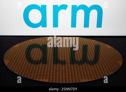 Das Logo der ARM Holdings auf dem Display und die unscharfe Reflexion auf dem Halbleiterwafer mit Mikrochips. Anschaulich für einen neuen Chip von ARM Company. St Stockfoto
