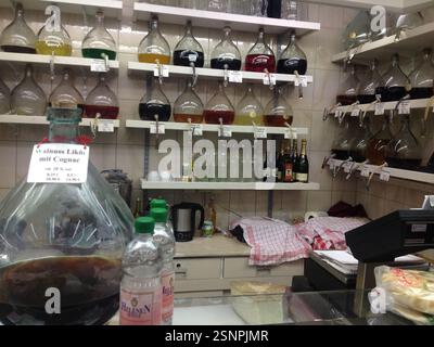 Spirituosengeschäft in Deutschland, München. Regale gefüllt mit Glasflaschen mit einer lebendigen Auswahl an farbenfrohen Flüssigkeiten. Vielfältige Auswahl an alkoholischen Getränken Stockfoto