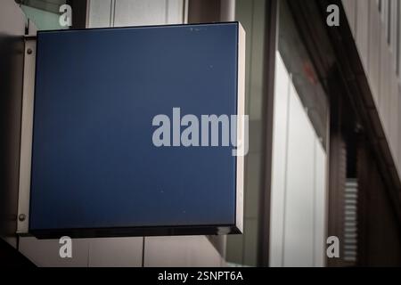 Vor einem deutschen Geschäft befindet sich ein leeres schwarzes quadratisches Schild, das minimalistischen Platz für Branding oder Werbung bietet. Die schlanke Metallrahmenverkleidung Stockfoto