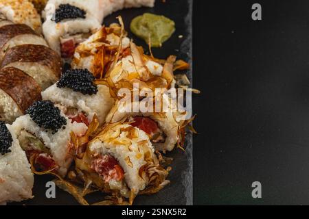 Eine lebendige Sushi-Platte zeigt eine Vielzahl von Brötchen, einschließlich Meeresfrüchten und Gemüse, garniert mit Kaviar und Wasabi, die die Kunstfertigkeit von hervorheben Stockfoto