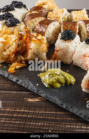 Eine wunderschön angeordnete Sushi-Platte zeigt eine Auswahl an Brötchen mit Kaviar und knusprigen Beilagen. Frischer Wasabi fügt einen Vibr hinzu Stockfoto