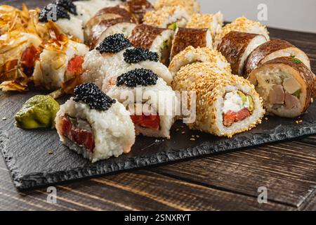 Eine wunderschön angeordnete Platte zeigt eine Auswahl an Sushi-Brötchen, jedes mit Kaviar und Sesamsamen verziert. Die frischen Zutaten sind lebendig Stockfoto