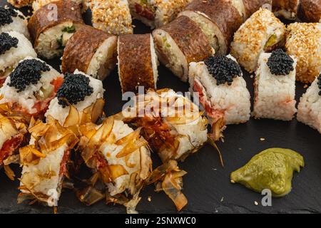 Eine wunderschön angeordnete Platte zeigt eine Vielzahl von Sushi-Brötchen, einschließlich traditioneller und kreativer Optionen, garniert mit Kaviar und Wasabi, Perfe Stockfoto