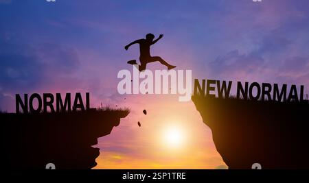 Silhouette Mann springt über neue normale Worte auf Klippen mit Wolkenhimmel und Sonnenaufgang. Neues normales und freiheitliches Challenge-Konzept. Stockfoto