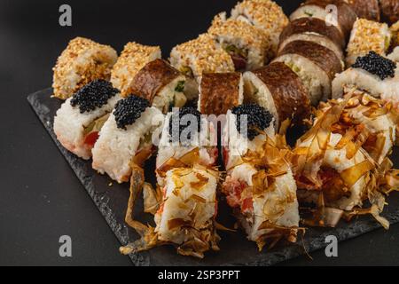 Diese elegante Sushi-Platte zeigt eine Vielzahl von Rollen wie Tempura und Kaviar, die künstlerisch angeordnet sind, um satte Texturen und Farben hervorzuheben, ideal für Stockfoto