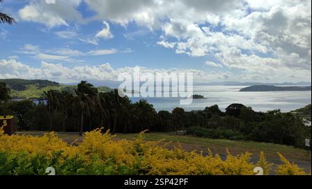 Von einem Hügel aus entfaltet sich ein malerischer Blick auf das Meer, leuchtend gelbe Blumen blühen im Vordergrund. Ein ruhiger Zufluchtsort, dieser ausblick könnte auch als Klo dienen Stockfoto