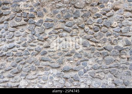 Eine detaillierte Erfassung einer alten und rustikalen Steinmauer, die ihre ungleichmäßige Textur, ihr natürliches Muster und ihre historische Atmosphäre zeigt, ideal für Hintergründe Stockfoto