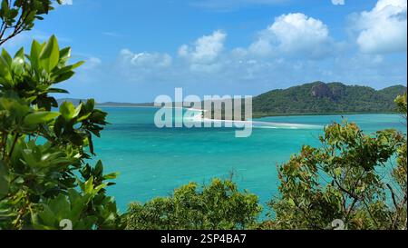 Eine tropische Insel verfügt über einen weißen Sandstrand und üppige grüne Hügel mit ruhigem türkisfarbenem Wasser am Ufer. Es ist ein idyllischer Urlaubsort, Re Stockfoto