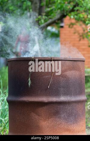 Rauchfass mit brennendem trockenem Gras im Gemüsegarten Nahaufnahme Stockfoto